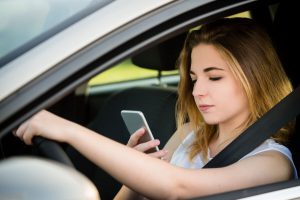 Une adolescente regarde son téléphone portable au volant d’une voiture